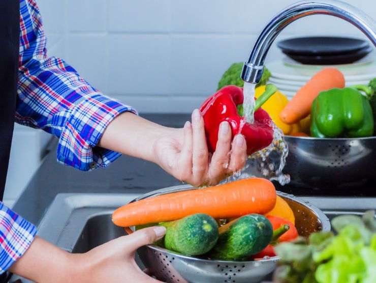 persona che sta lavando della verdura sotto l'acqua