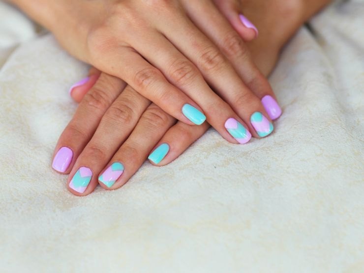 mani di donna con unghie tutte colorate e a fantasia