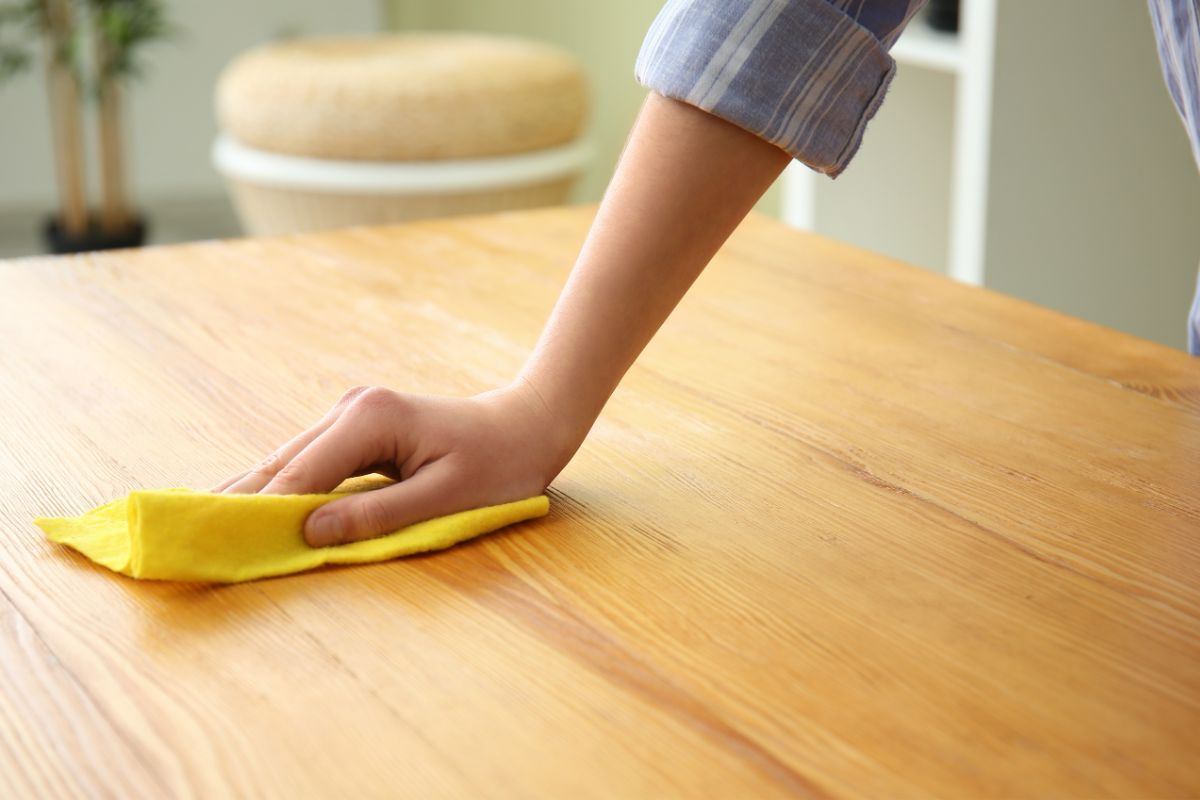 donna che pulisce superficie mobile in legno