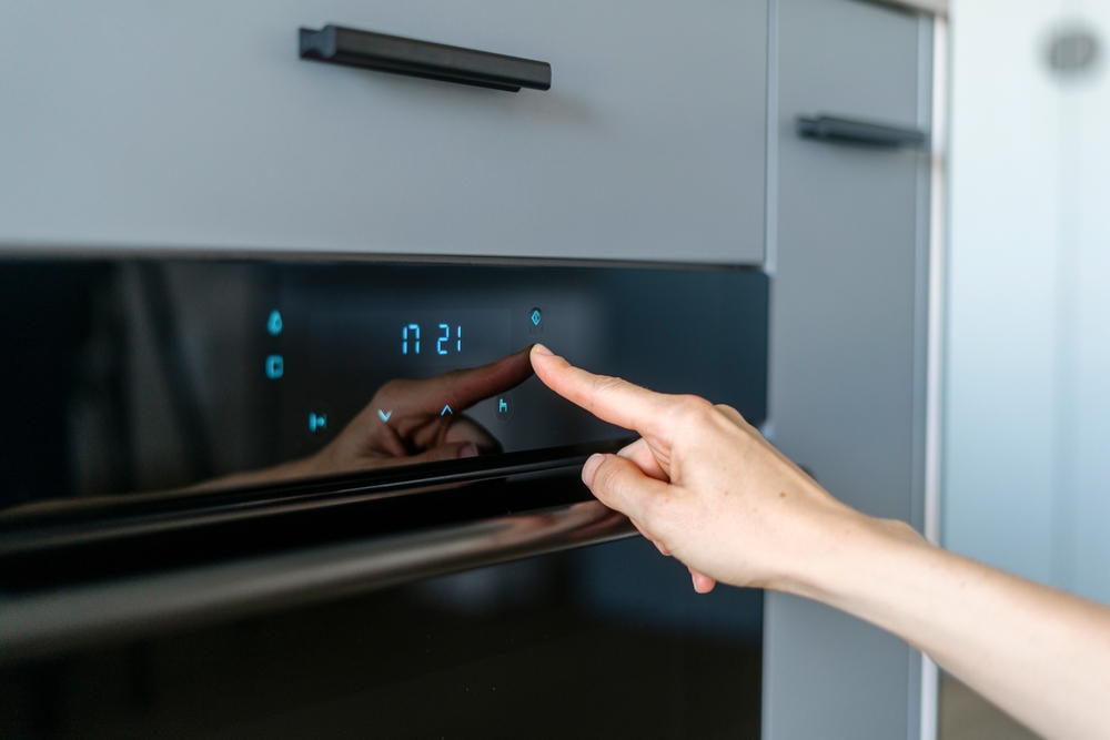 Forno elettrico intelligente con pulsanti touch toccati da una donna 